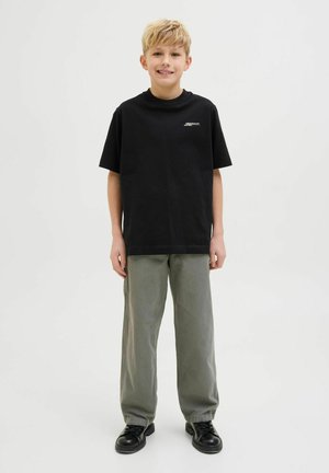 T-shirt en coton noir à coupe décontractée et à manches courtes, associée à un pantalon vert clair et des chaussures noires. Design simple et décontracté.