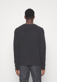 Dunkelgrauer, strukturierter Strickpullover mit rundem Halsausschnitt und langen Ärmeln. Hat eine leicht übergroße Passform und einen Saum, der in der Taille endet.