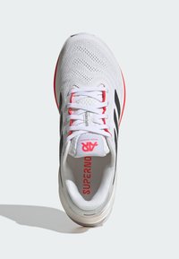 Baskets de course blanches avec des rayures noires, dessus en mesh respirant, accents roses contrastants, bout rond et semelle rembourrée pour plus de confort.