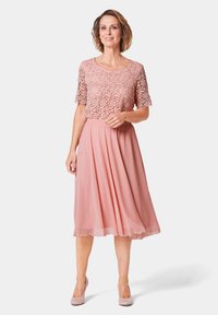 Roze jurk met een bloemenkant top en een vloeiende chiffon rok. Heeft korte mouwen en een elastische tailleband voor comfort.