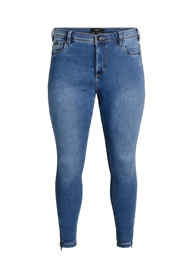 Plave traperice uskog kroja s visokim strukom, prednjim džepovima i detaljima rajsferšlusa na gležnjevima. Tekstura tkanine blago izblijedjela.