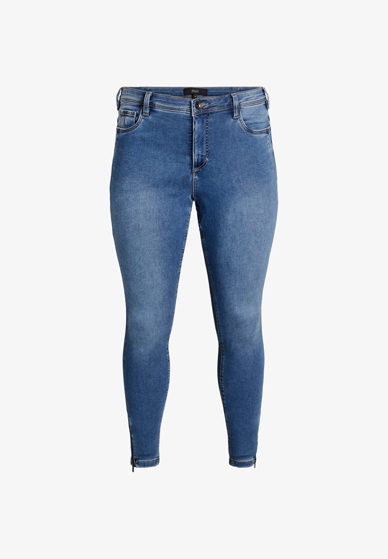 Plave traperice uskog kroja s visokim strukom, prednjim džepovima i detaljima rajsferšlusa na gležnjevima. Tekstura tkanine blago izblijedjela.