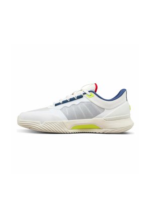 Weißer Sportschuh mit blauen und roten Akzenten, gelben Details, strukturierter Sohle und Netzseitenteil, von der Außenseite betrachtet.