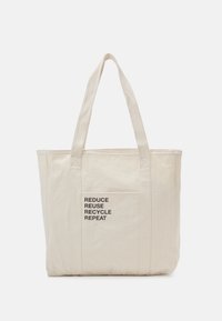Cotton tote bag in light beige with two sturdy handles and a front pocket featuring black printed text: "REDUCE REUSE RECYCLE REPEAT."