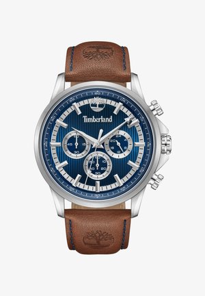 Srebrn kronograf iz nerjavnega jekla z modrim teksturiranim številčnico, tremi podštevilkami in rjavim usnjenim pasom z modrim šivanjem.