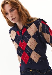 Pullover lavorato a maglia in navy, rosso e beige con un motivo a rombi; presenta un colletto a polo e una pattina con tre bottoni; orlo a coste.