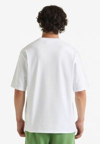 T-shirt bianco in cotone con maniche corte, colletto rotondo e vestibilità ampia. Design semplice, senza loghi o fantasie visibili.