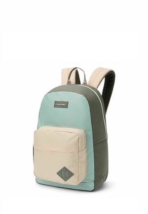 Backpack with padded beige straps, front beige zip pocket, and main body in green and light blue, Dakine logo on front.