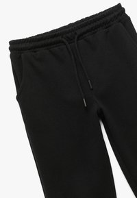 Zwarte joggingsbroek met een elastische tailleband, trekkoorden, zijzakken en een zachte, gestructureerde stof. Recht model.