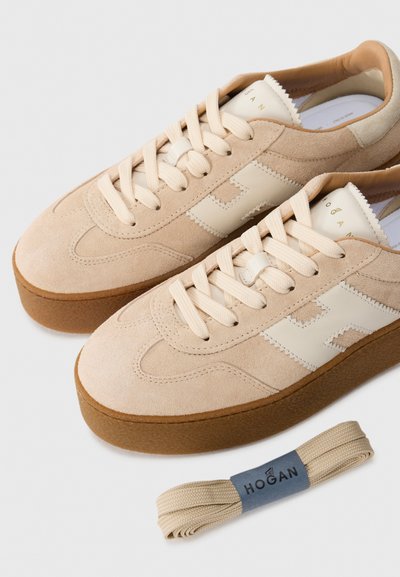 Tan suède sneakers met een lichtbeige embleem en veters. Dikke rubberen zool. Inclusief een extra paar beige veters met branding.