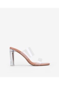 Mules de tacón transparente con dos tiras transparentes y una plantilla en tono nude. Tacón bloque recto, alto y transparente. Acabado suave y brillante.