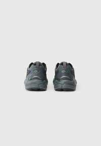 Adidași negri cu un superior texturat, talpă rotundă și guler căptușit. Prezentă detalii subtile cu logo și accente de culoare în două tonuri.