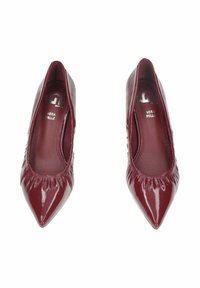 Pumps in pelle verniciata bordeaux con punte affusolate e dettagli arricciati alle aperture, caratterizzati da una texture liscia e lucida.