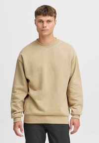 Beige katoenen sweatshirt met ronde hals, lange mouwen en geribde manchetten en zoom. Gladde textuur, relaxte pasvorm, minimalistisch design.