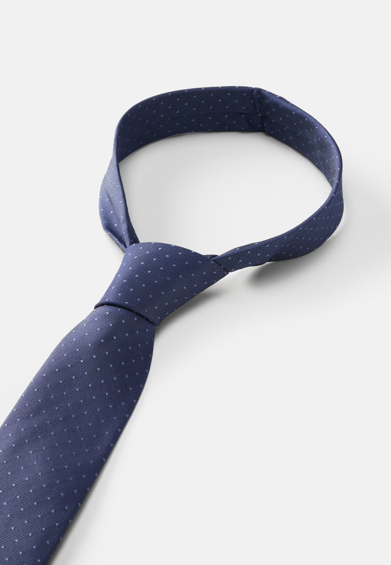 Mörkblå slips med små, jämnt fördelade ljusblå prickar. Tillverkad av mjukt tyg, med en klassisk design som har en smal ände och en knut.