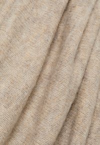 Beżowa tkanina wełniana o miękkim, teksturowanym wykończeniu, ukazująca subtelny, nierówny wzór tkania oraz naturalną, ziemistą wariację kolorów.