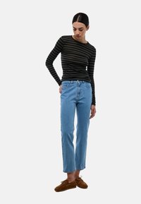 Haut à rayures à manches longues en vert foncé et noir, associé à un jean droit bleu clair et des chaussures en suède marron à lacets.