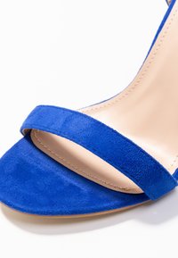 Sinisinen mokkakengät korkealla korolla, joissa on leveä varvasremmi ja kapea nilkkaremmi. Sileä nude-värinen sisävuori ja tukeva pohja.