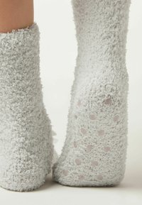 Szare, puszyste skarpetki o miękkiej fakturze. Podeszwy mają różowe kropki zapewniające przyczepność. Rękawy są grube i przytulne, co zwiększa ciepło.