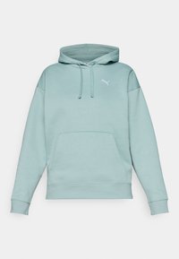 Gaismi piparmētru zaļš hoodie, kas izgatavots no mīksta auduma, ar vaļu kabatu, auklām un mazu baltu logo uz krūtīm.
