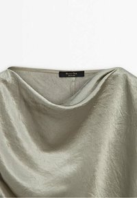 Tissu satin gris clair avec un col drapé et une étiquette de vêtement noire visible portant la mention "Massimo Dutti."