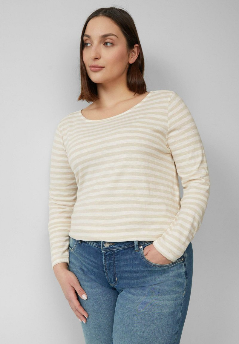 Gestreepte longsleeve top in lichtbeige en crème, met een ronde halslijn en zachte textuur, gecombineerd met mid-blauwe spijkerbroek.