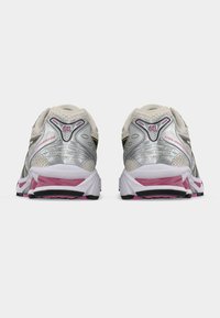 Ζευγάρι παπουτσιών για τρέξιμο Gel-Kayano σε μπεζ, ασημί και ροζ χρώμα, από πίσω, πάνω σε λευκό φόντο.