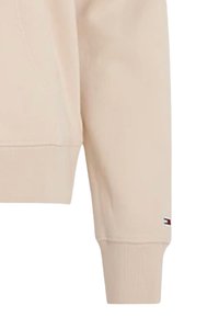 Felpa beige chiaro in misto cotone, con collo rotondo, polsini a coste e un piccolo logo sulla manica. Texture liscia.