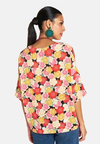Floral print blouse with short sleeves. Features red, pink, and yellow flowers on a black background. Soft fabric, relaxed fit, round neckline.
