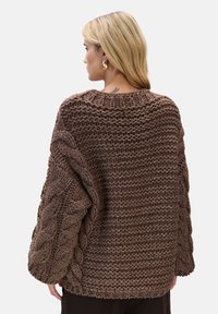 Brązowy sweter z grubym splotem, o luźnym kroju, grubym splocie, szerokich rękawach i prążkowanym dekolcie, prezentujący misternie tkane detale.