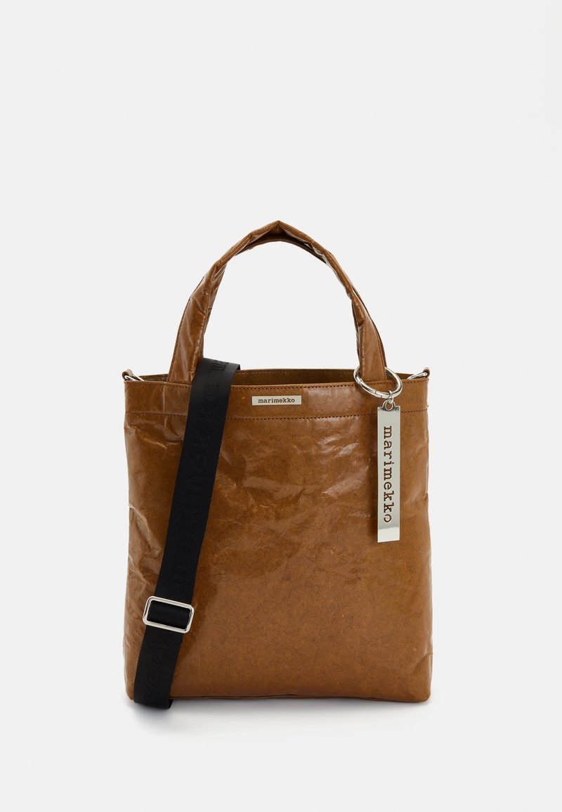 Sac cabas en cuir marron avec deux poignées, une bandoulière noire réglable et une étiquette blanche portant la mention "marimekko" suspendue à une poignée.