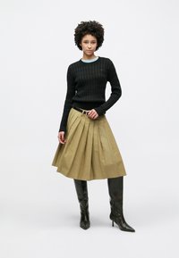Pull noir en tricot texturé, jupe plissée beige et bottes noires à talons montantes jusqu'aux genoux. Comprend une ceinture avec une boucle argentée. Design simple et structuré.