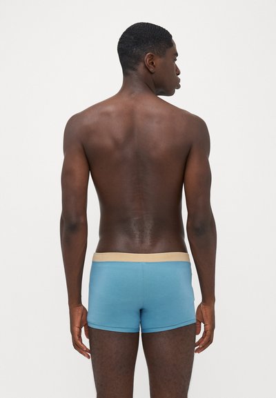Men's boxers in light blue fabric with a contrasting beige waistband, featuring a smooth texture and a fitted design.