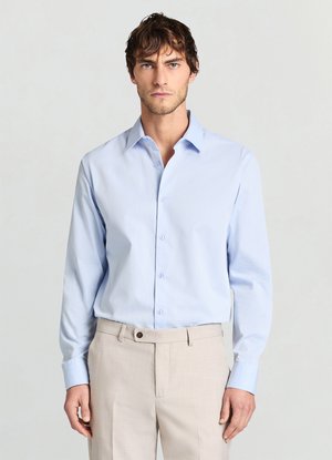 Hellblaues Hemd mit Knopfleiste, strukturiertem Kragen und langen Ärmeln aus strukturiertem Stoff, kombiniert mit hellbeigen, maßgeschneiderten Hosen.