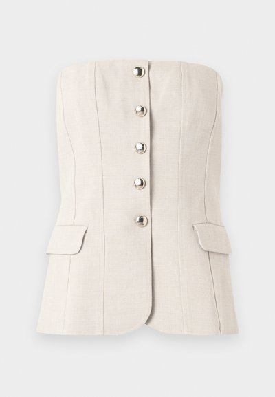 Μπεζ κορυφή χωρίς τιράντες με μεταλλικά κουμπιά μπροστά και δύο τσέπες με καπάκι στη μέση, δομημένη με κάθετες ραφές.