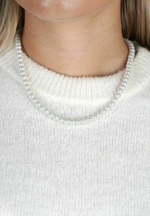 Vit stickad tröja med ett kort pärlhalsband, bestående av små, runda, glänsande pärlor i en enhetlig ljusgrå färg.
