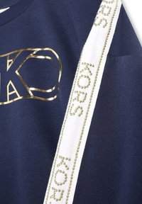 Navy cotton sweatshirt with a metallic gold logo and white side stripe adorned with beads spelling "KORS." Smooth texture, casual design.