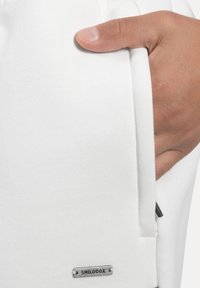 Weiße Jogginghosen aus Baumwolle mit Seitentaschen, aus strukturiertem Stoff, mit elastischem Bund und kleinem metallischem Logotag.