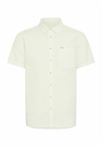 Camisa de manga corta, de color claro, con un tejido texturizado, cierre de botones en la parte delantera y un bolsillo en el pecho. Presenta una etiqueta de marca sutil en el bolsillo.