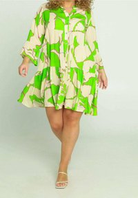 Korte mouwen jurk in crème met grote groene en roze abstracte patronen. Knopen aan de voorkant, gelaagde rok en ontspannen pasvorm. Gladde stoftextuur.