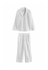 Ensemble de pyjama blanc deux pièces avec haut boutonné à manches longues et pantalon à taille élastique, avec des rayures verticales discrètes et une poche poitrine.
