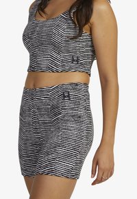 Black and white striped cropped tank top with matching high-waisted shorts. Fabric has a textured feel, featuring small tags on both pieces.