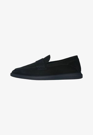 Black suede slip-on shoes with a tapered design, stitched detailing, and a navy rubber sole. Features a decorative strap across the upper.