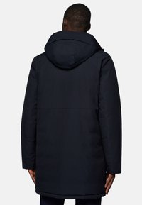 Navy blue padded coat with a hood, featuring a smooth texture and a slightly longer cut, visible seams, and an adjustable neckline.