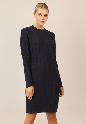 Marineblaues gestricktes Kleid mit einem Diamantmuster, langen Ärmeln sowie gerippten Bündchen und Saum. Weicher Stoff und figurbetonte Silhouette.