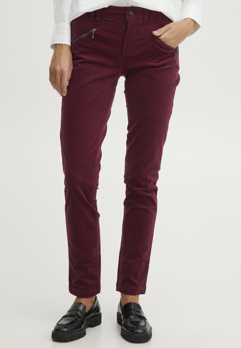 Burgundy kordflorsbyxor med slim fit, med fickor fram med dragkedja och robust sömnad, i kombination med svarta loafers.