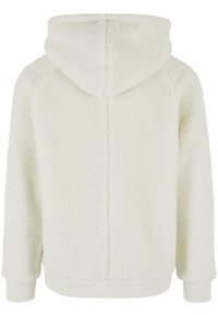Veste en polaire blanche et duveteuse avec capuche, manches longues et poignets côtelés vue de dos.