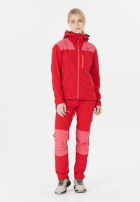 Veste et pantalon imperméables rouges avec des accents roses, dotés d'une poche poitrine zippée et d'une capuche ajustable. Fabriqués en matériau durable et léger.