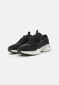 Black athletic sneakers with synthetic and mesh materials. Features a rounded toe, textured upper, and contrasting white midsole accents.