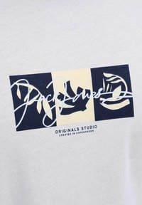 T-shirt i bomuld med et grafisk design med tre farveblokke: mørkeblå, creme og lys gul, samt teksten "Jack Jones" i kursiv.